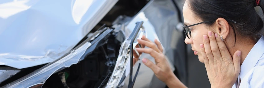 A woman is looking at a person's car from a car accident case.