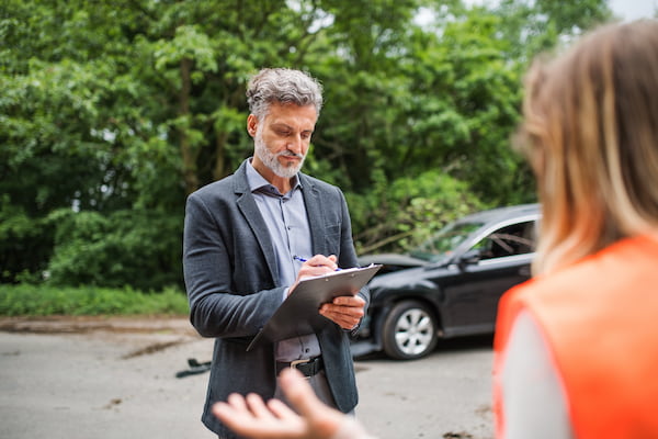 A woman talking to an insurance adjuster after a car accident