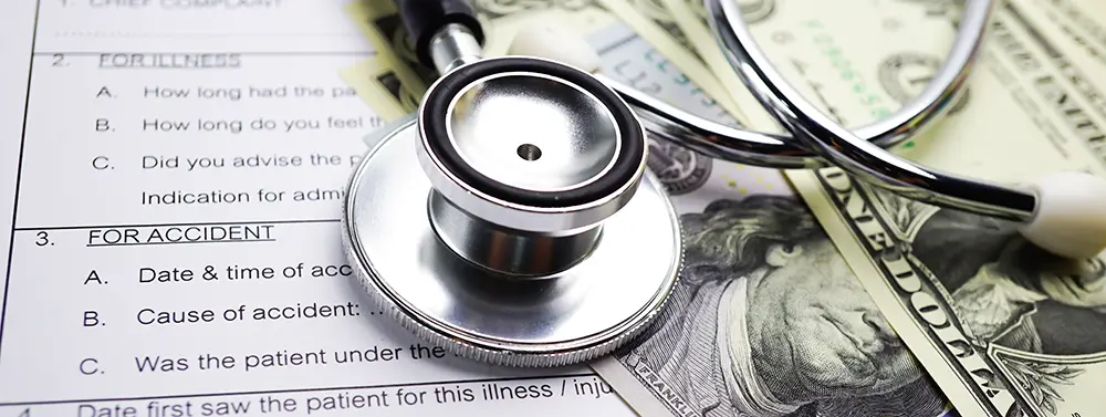 a money and stethoscope on top of a car accident report form